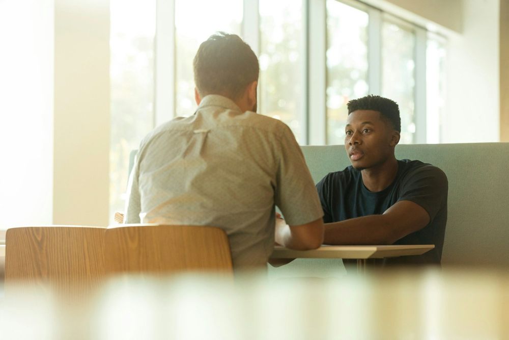 A mentor talking one-on-one with a young man at a table