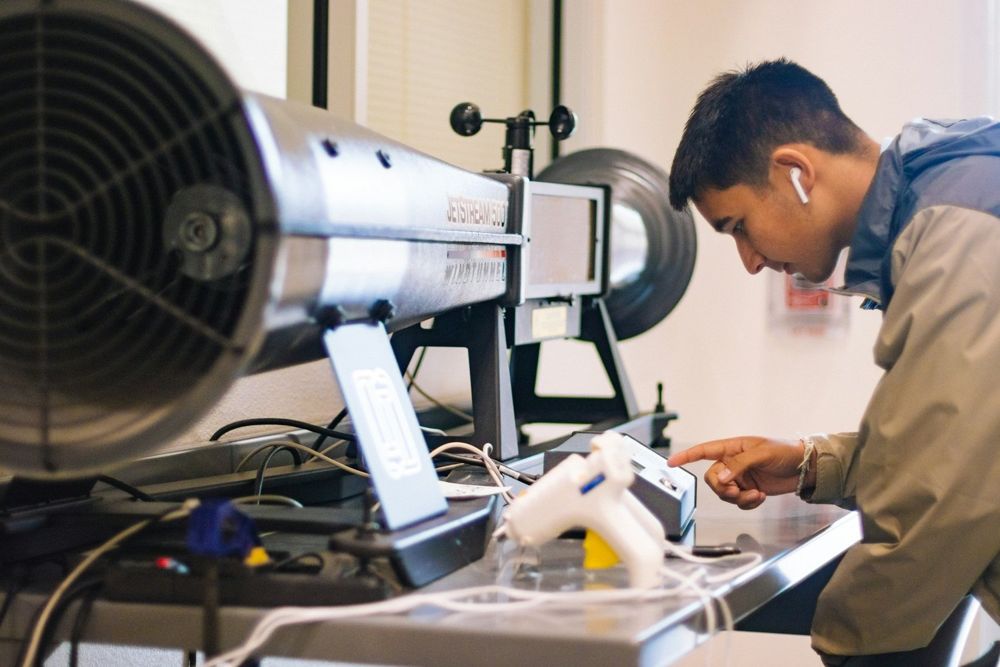 A young man working with laptop and lab equipment in a workshop