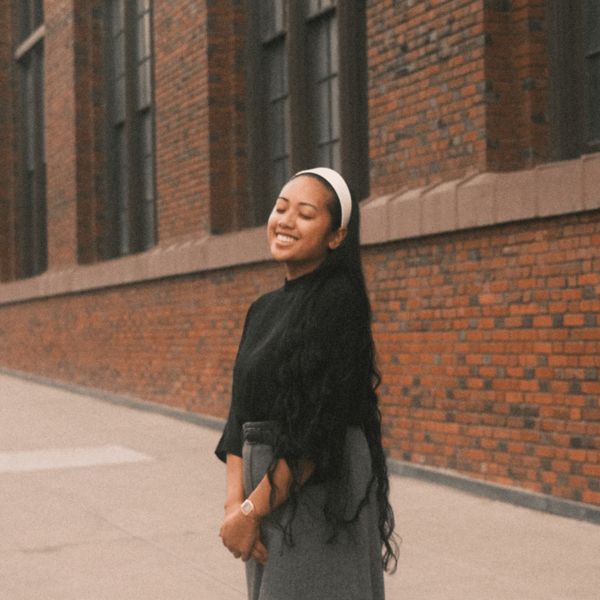 Darlene Lacsamana smiling, standing outside a brick building